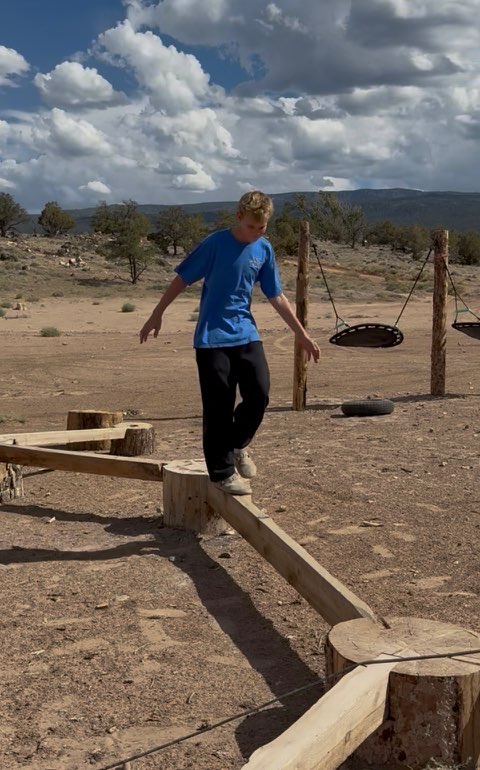 Child balancing on wooden beams in the natural playground