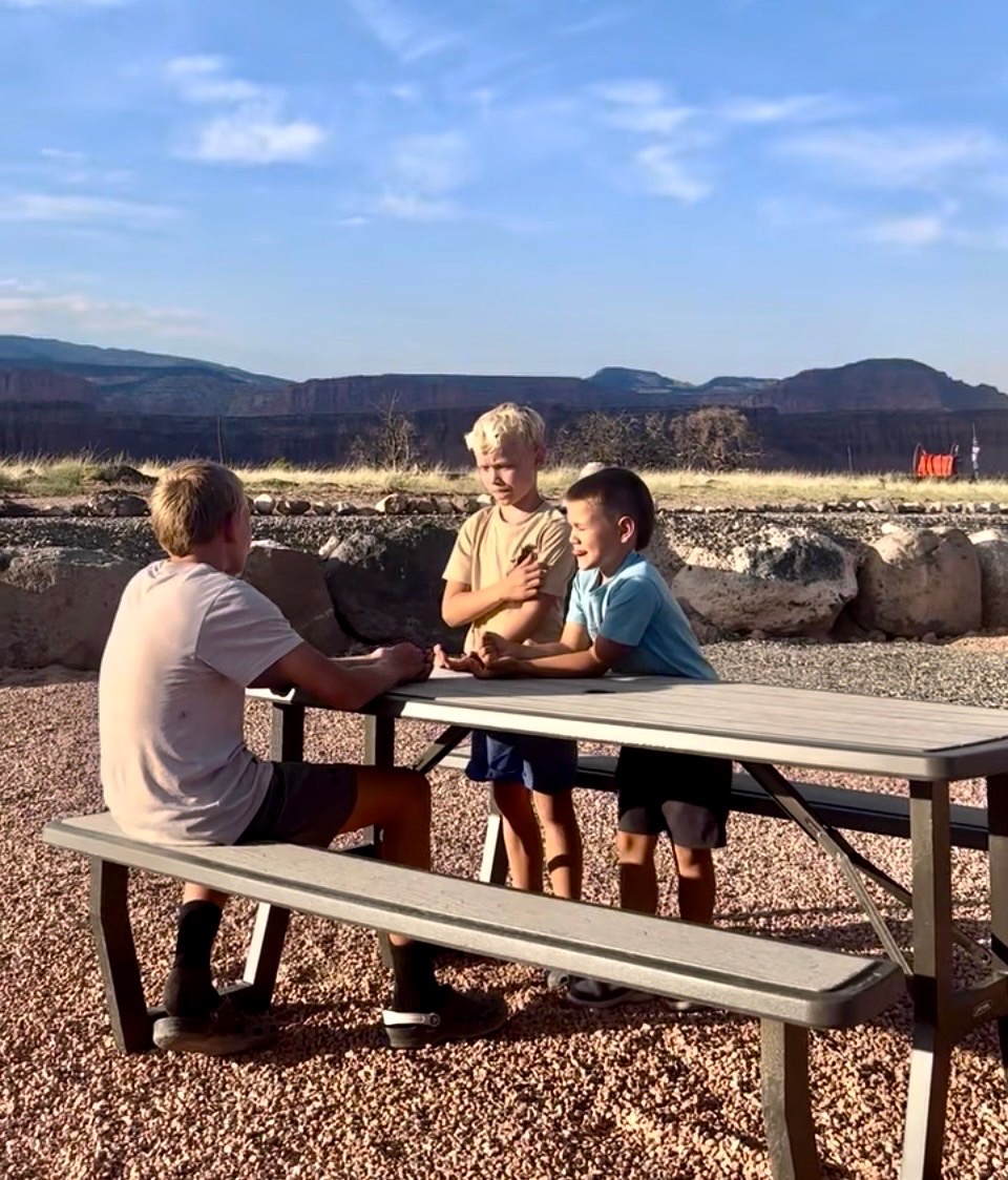 Children at a picnic table with red-rock cliffs behind