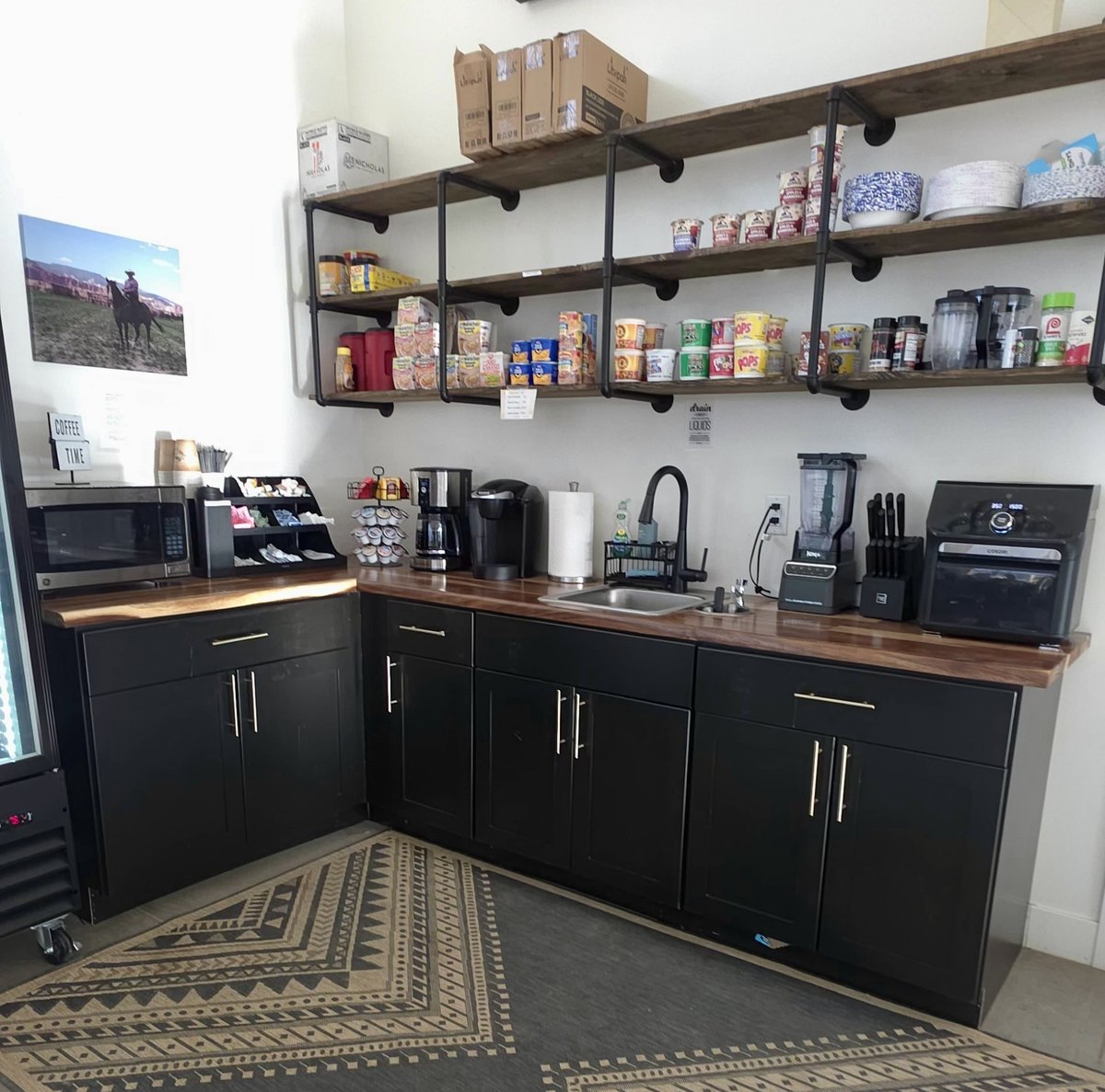 Coffee station and kitchenette with a sink, counter and shelves