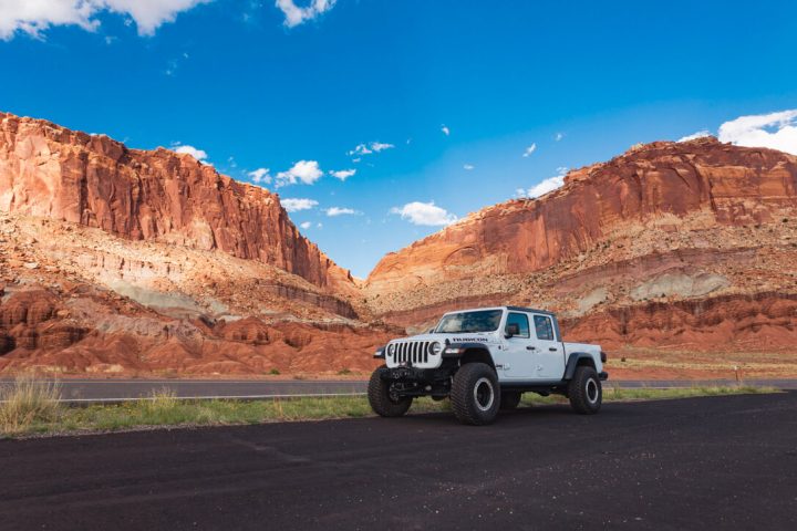 Jeep beside red rock cliffs in Capitol Reef National Park, Utah